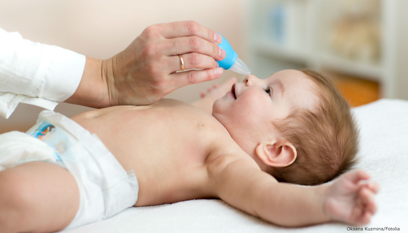 Mulher desentupindo nariz de bebê.